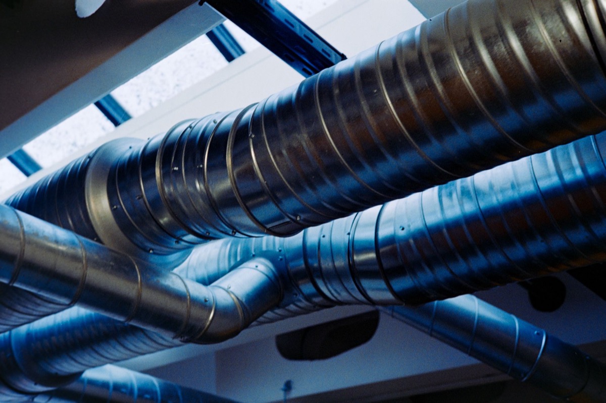 Round galvanized steel supply ducts branching from a trunk line in an unfinished residential basement ceiling